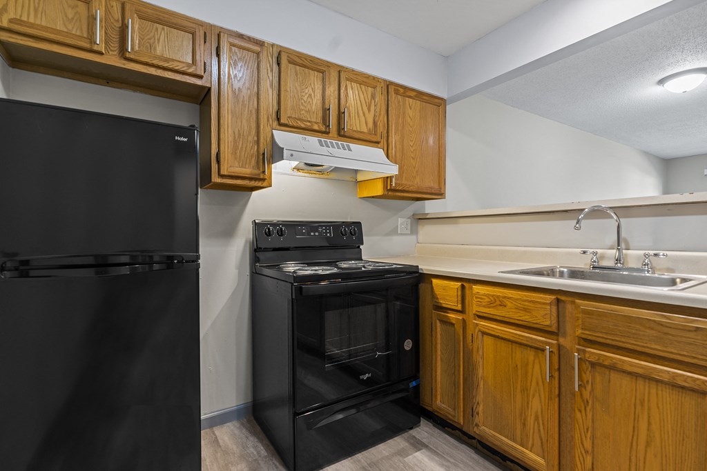 a kitchen with black appliances and wooden cabinets and a sink