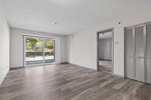 the living room of an apartment with a large window and a door to the yard