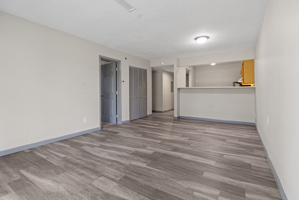 the living room and kitchen in a new home with a wood floor and white walls