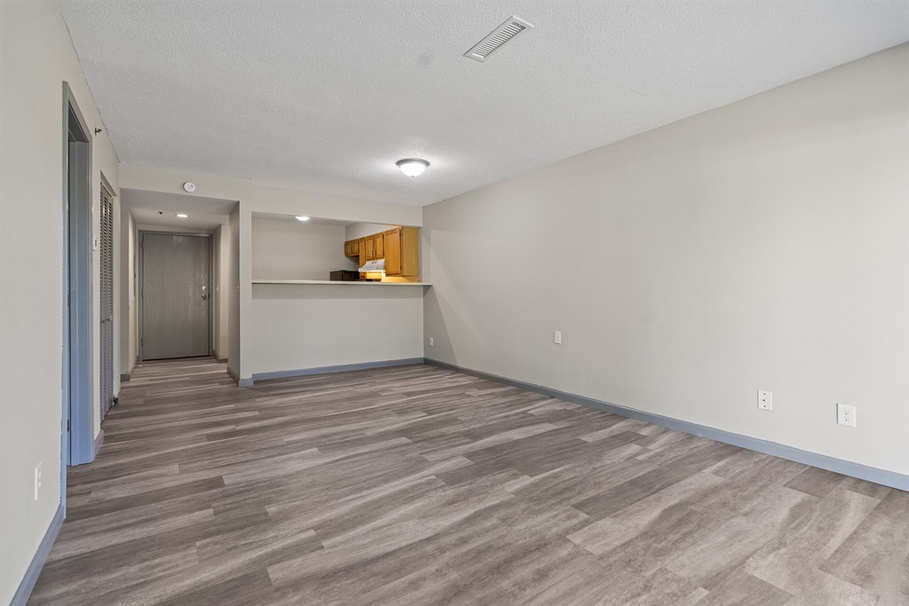 the living room is empty and has a door to the kitchen
