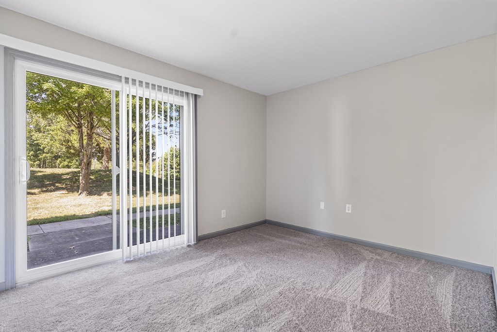 an empty living room with a large window and a door to the yard