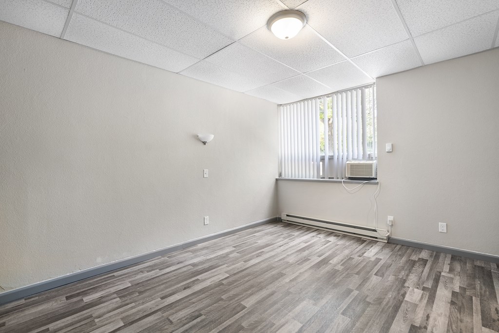 an empty living room with wood flooring and a window