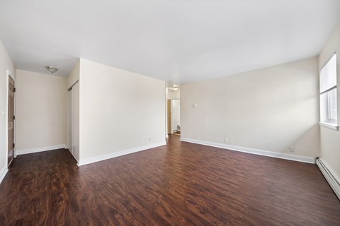 an empty living room with wood flooring and white walls