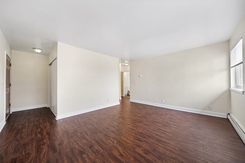 an empty living room with wood flooring and white walls