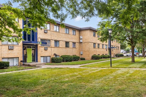 a large brick apartment building with green grass and trees