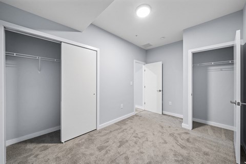 A spacious room with carpeted floor and three open closet doors.