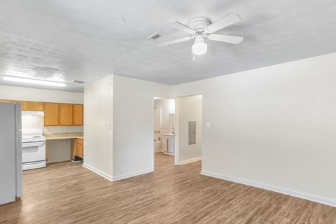 an empty living room and kitchen with a ceiling fan