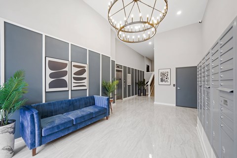 A blue sofa sits in a spacious room with a chandelier hanging from the ceiling.