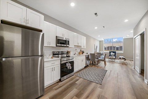 A modern kitchen with a stainless steel refrigerator and wooden floors.