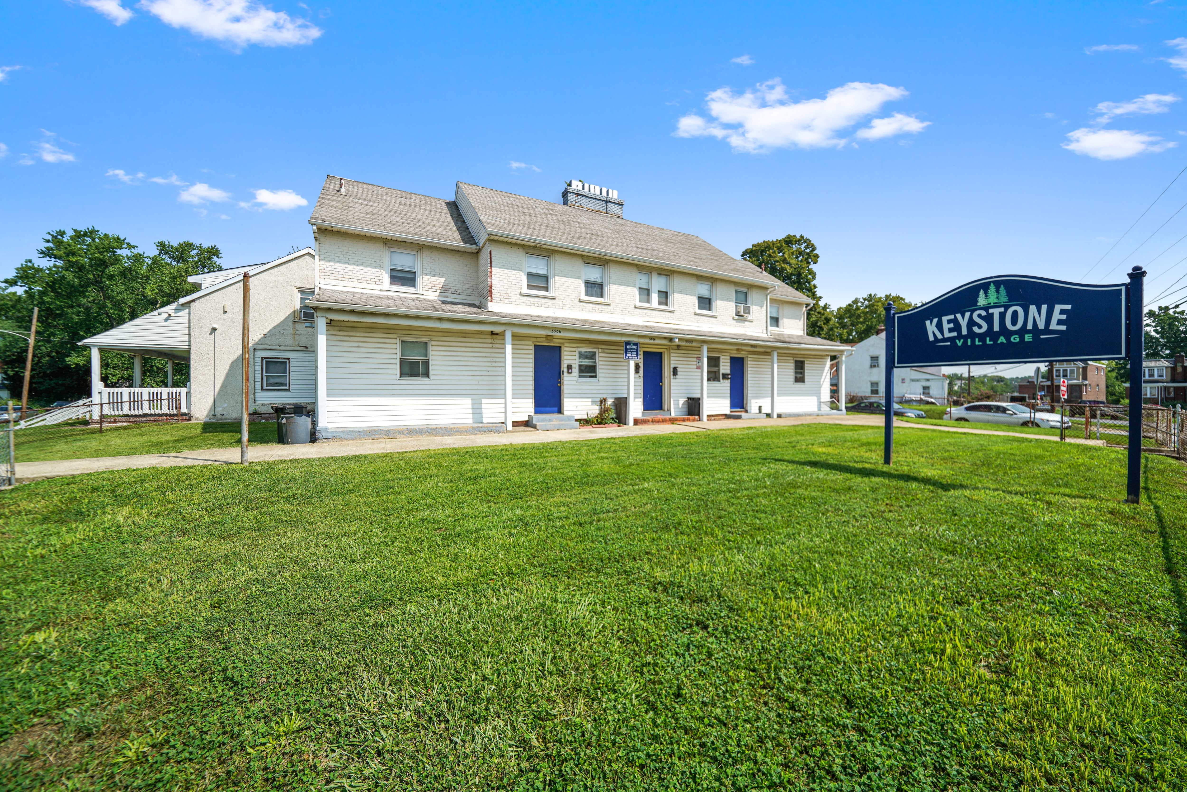 a white motel with a green sign in front of it