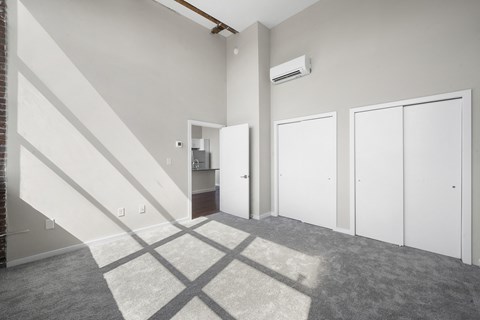 A room with a carpeted floor and a staircase leading to another room.