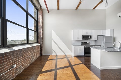 A kitchen with a white counter top and a staircase leading to the upper floor.