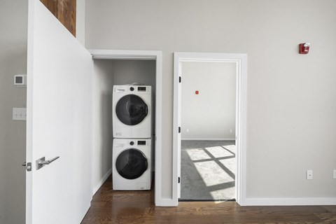 A white door is open to a room with a washer and dryer in it.