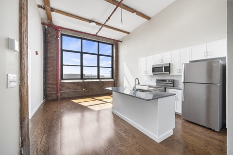 A kitchen with a refrigerator, sink, and window.