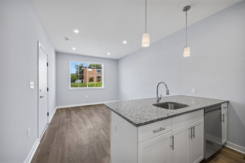 A kitchen with a granite countertop and a view of a building outside the window.