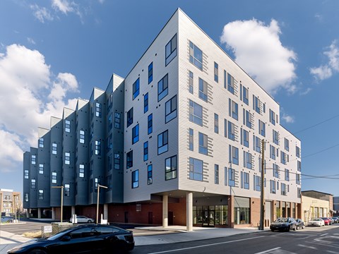A modern building with a white and grey facade stands on a street corner.