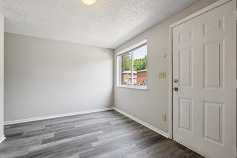 A room with a white door and a window showing a view of a building outside.