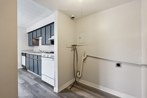 A kitchen with a stove top oven and a wall with a pipe running along it.