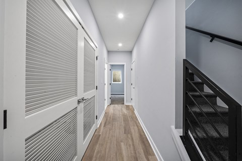 A long hallway with a staircase on the right and a door at the end.