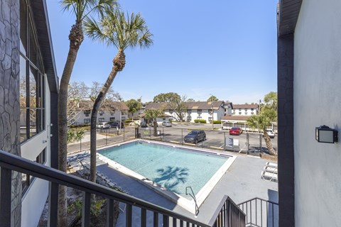 A pool surrounded by a fence and a few trees.