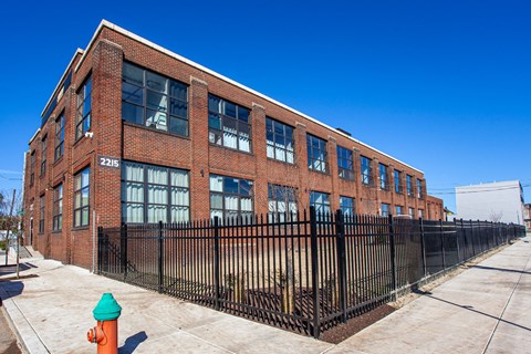 A red brick building with a black fence and a green fire hydrant in front.