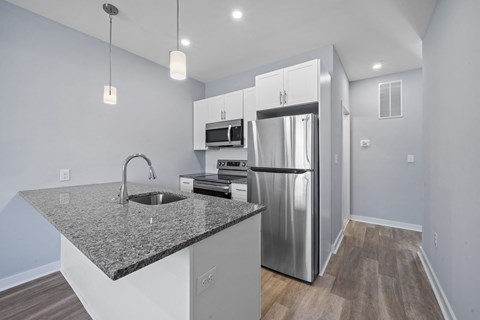A kitchen with a granite countertop and stainless steel appliances.