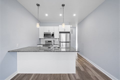 A modern kitchen with a granite countertop and pendant lights.
