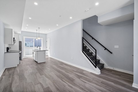 A spacious room with a staircase and a kitchen area.