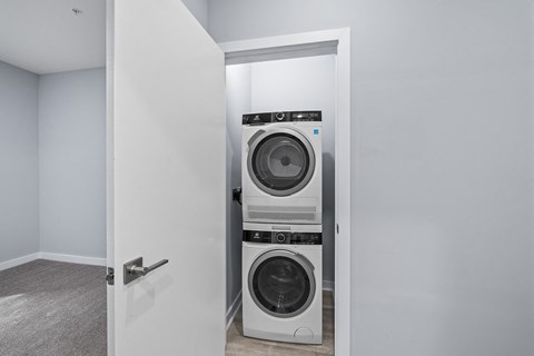 A white door opens to a laundry room with a washer and dryer.
