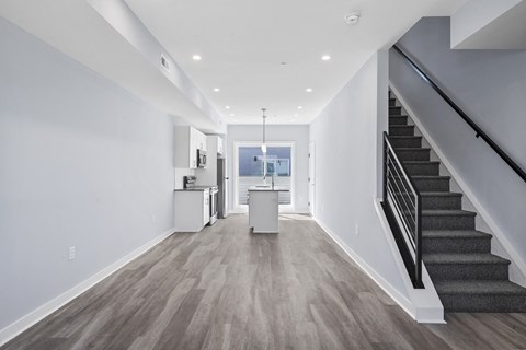 A long hallway with a staircase on the right and a kitchen area on the left.