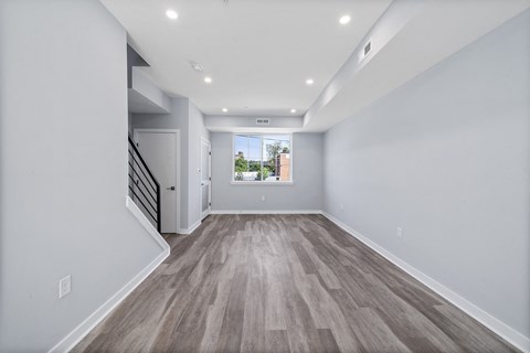 A long hallway with wood flooring and white walls.