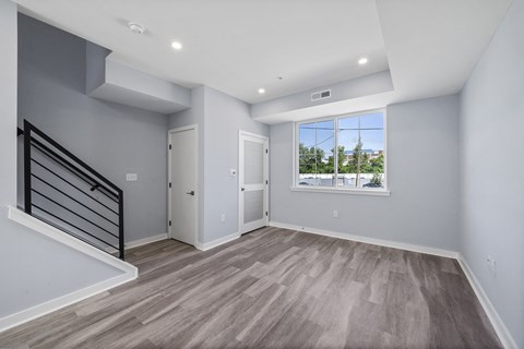 A spacious room with a staircase and a view of the outdoors through a window.