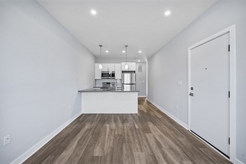 A kitchen with white walls and a wooden floor.