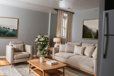 A living room with a couch, chair, and a painting on the wall.
