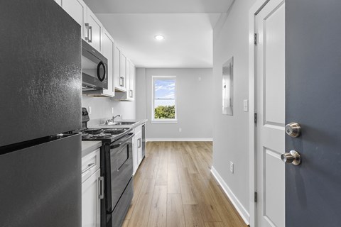 A kitchen with a black fridge and stove top oven.