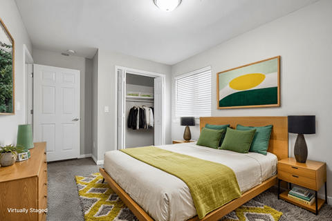 A bedroom with a bed, nightstand, and a painting on the wall.