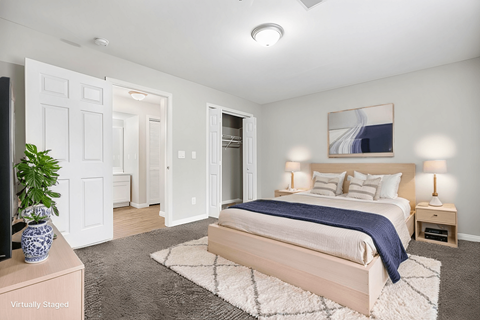 A bedroom with a bed, nightstands, and a plant.