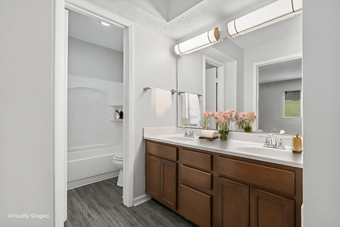 A bathroom with a white counter and brown drawers.