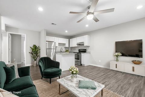 A living room with a green couch, a black chair, and a white coffee table.