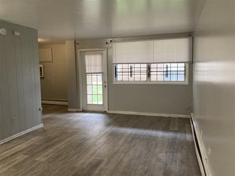 A room with wooden flooring and a window with blinds.