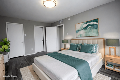 A bedroom with a large bed and a painting on the wall.