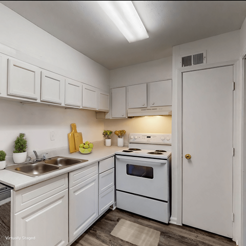 A white kitchen with a sink, stove, and cabinets.