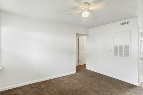 a living room with white walls and a ceiling fan