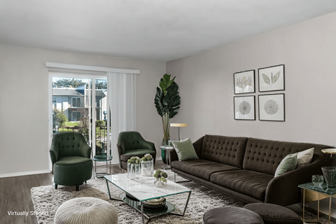 A living room with a brown couch, green armchairs, and a glass coffee table.