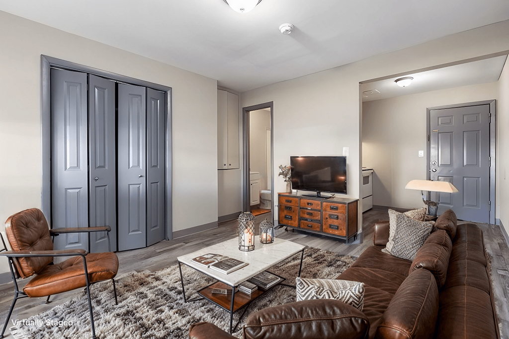 A living room with a brown leather couch, a coffee table, and a chair.