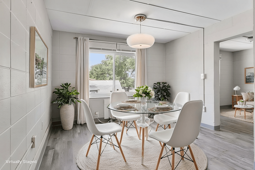 A dining room with a glass table and white chairs.