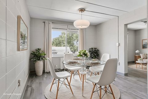 A dining room with a glass table and white chairs.