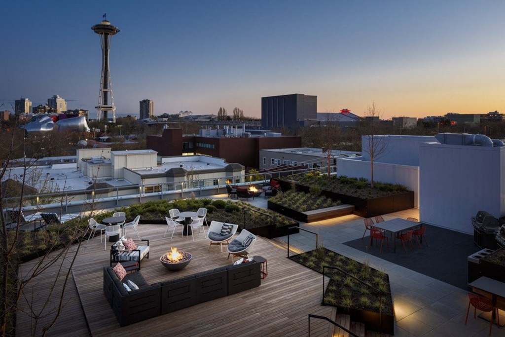 a rooftop terrace with a table and chairs and a city in the background