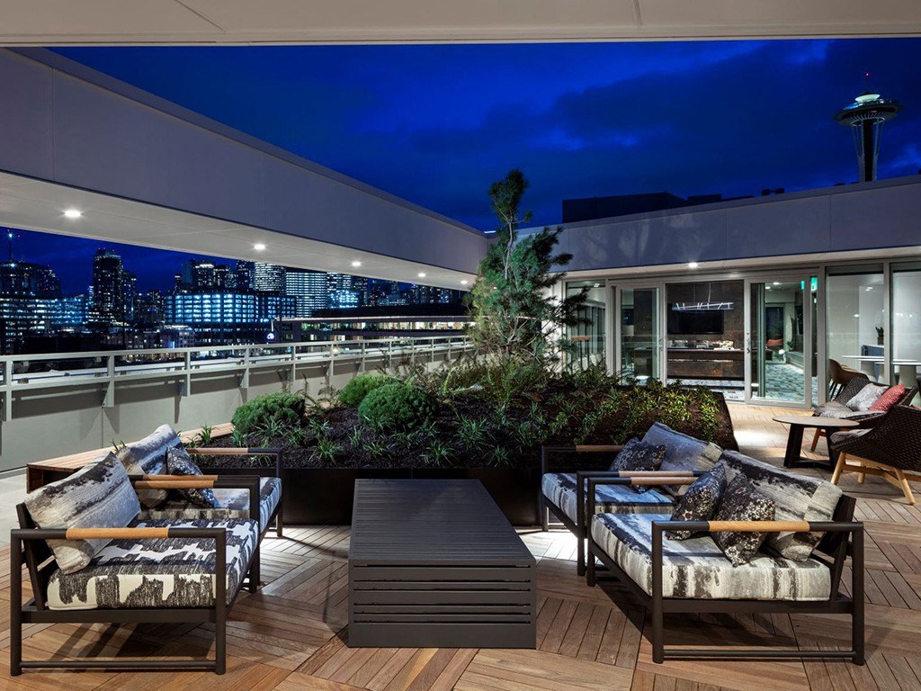 a roof top patio with furniture and a city at night