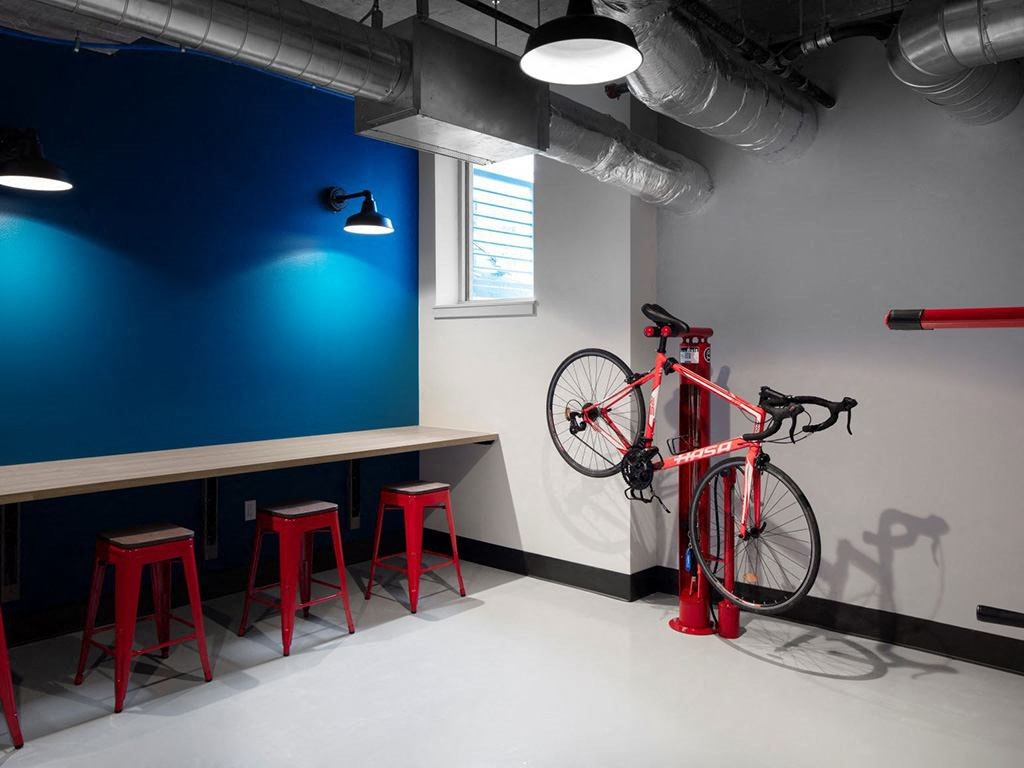 a bike is hanging on the wall in a room with red stools